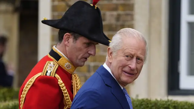 Close up of King Charles looking sideways to his right as he enters a building