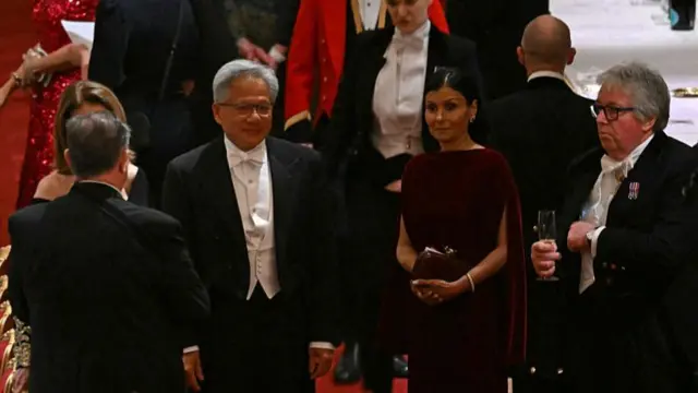 Nvidia CEO Jensen Huang stands with other attendees. The edge of the table can be seen