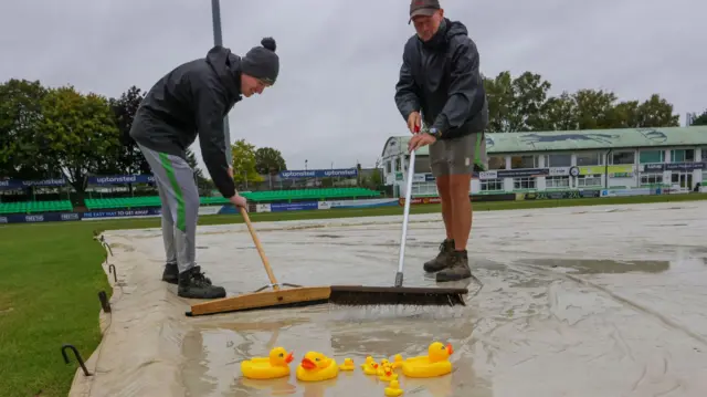 Groundstaff mopping up at Leicestershire with toy ducks on the wet covers
