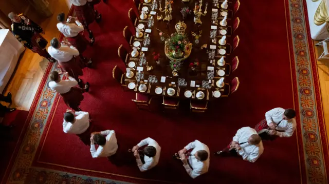 An overhead shot of a line of pipers as they practice at the edge of the table