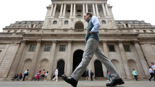 A man walking past the Bank of England building