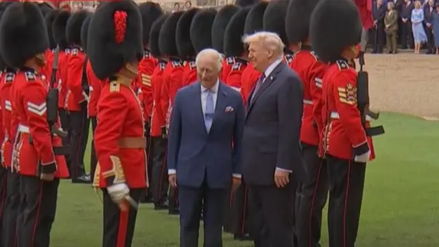 King Charles (L) and a smiling Donald Trump stand on the lawn of Windsor Castle as they inspect the troops