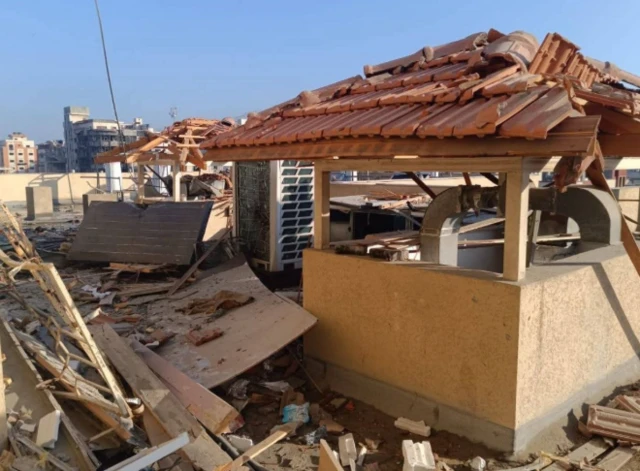 A picture of a heavily damaged hospital rooftop, rubble strewn all over it and a air conditioning unit is damaged