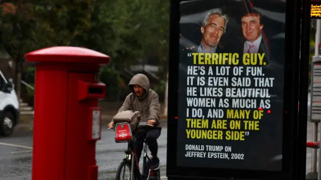 A man bikes past a poster of Donald Trump and Jeffrey Epstein at a bus stop in London