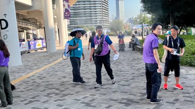 A volunteer sprays mist to help keep fans cool
