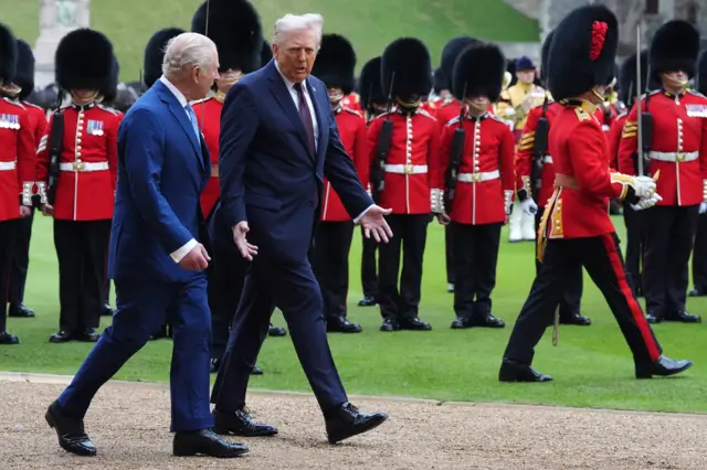 King Charles (L) listens to Donald Trump (R) speak as they walk along the lawn outside Windsor Castle