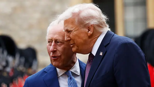 King Charles (L) speaks as Donald Trump (R) leans towards him