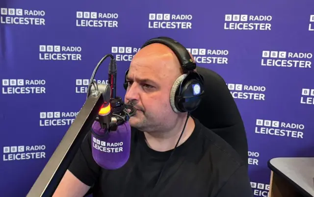 Ady Dayman at the mic in a radio studio