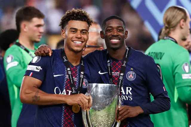 Desire Doue and Ousmane Dembele smiling for a picture with the Uefa Super Cup trophy