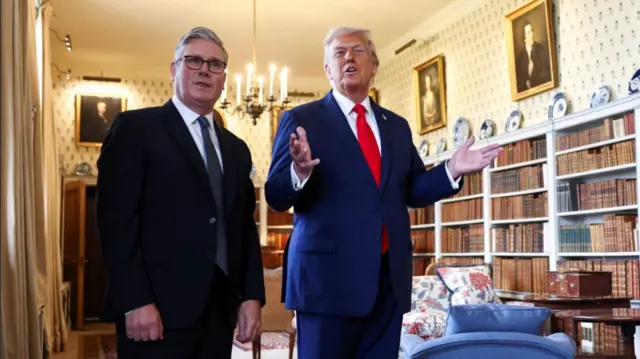Keir Starmer (L) stands next to Donald Trump (R) as he shows him around one of the room of Chequers. Several bookcases filled with books fill the background