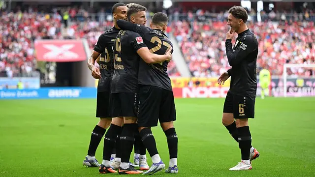 Stuttgart players in black celebrate a goal together.