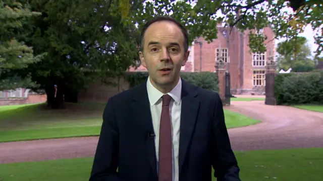 James Murray stands in front of Chequers in a suit as he is inteviewed.