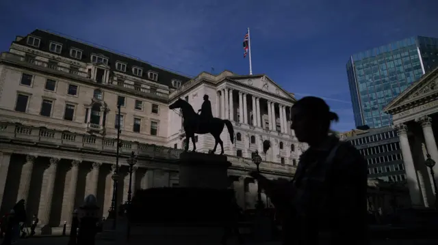 The silhouette of a person against a backdrop of the Bank of England in the City of London