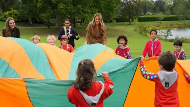 Kate and Melania playing with young children and lauging