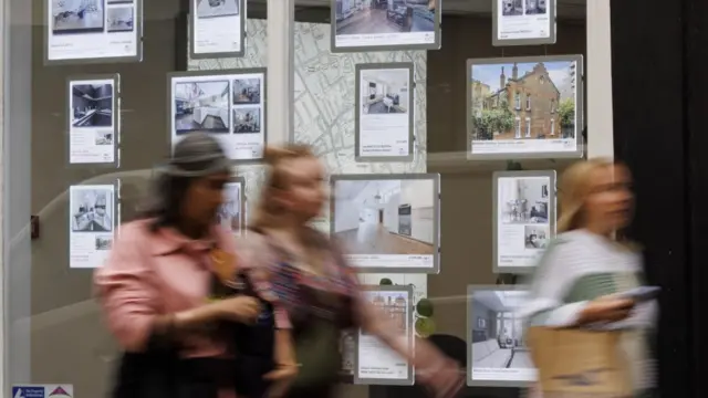 People walk past an estate agent in London