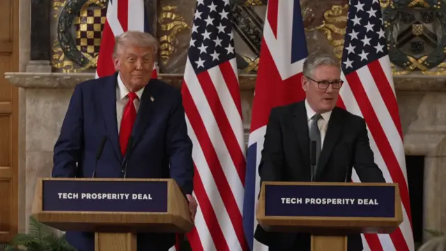Trump smiles at the reporters gathered in the room out of frame as Starmer speaks