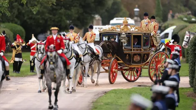 The ornate carriage being drawn by horses and troops lining the way. You can see Donald Trump sitting inside.
