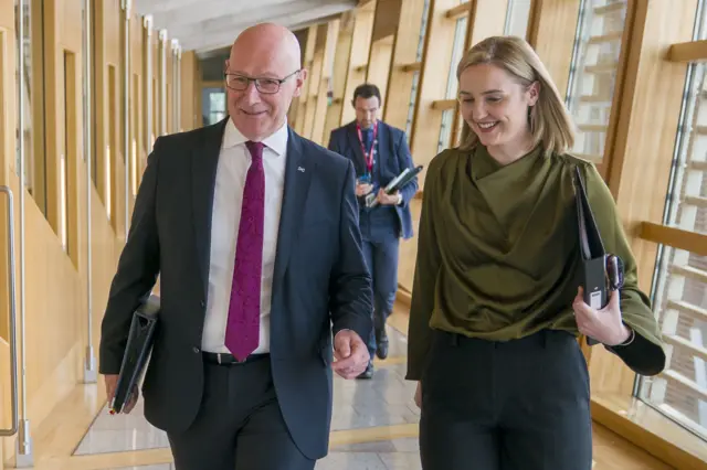 John Swinney and Mairi McAllan walking down a corridor in Holyrood