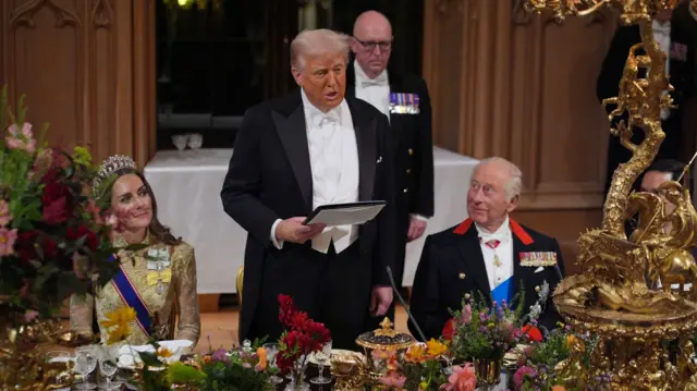 Donald Trump (C) stands in between the Princess of Wales (L) and King Charles (R) as he delivers a speech during the state banquet. There's a lavishly set out table in front of them