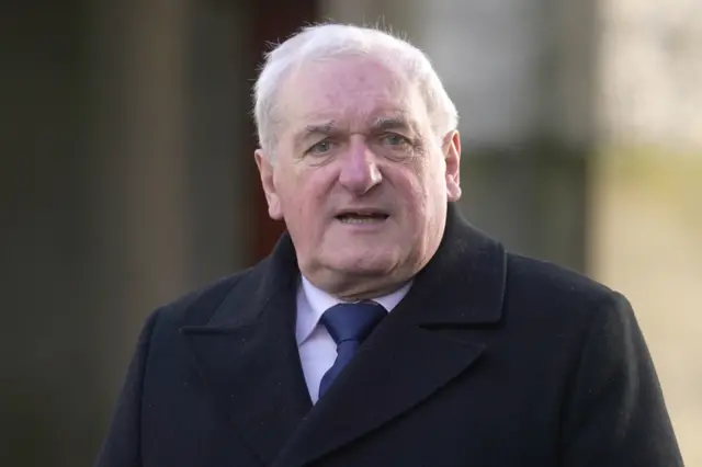 Bertie Ahern is wearing a shirt and a navy tie with a black jacket