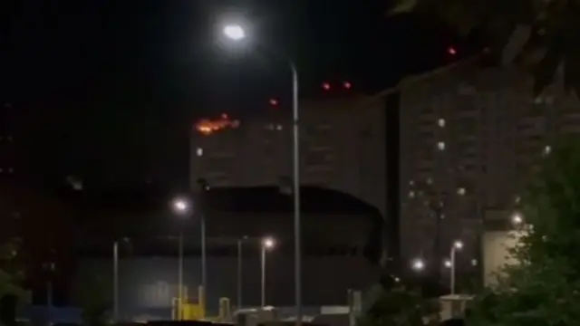 A grab from a verified video showing a fire in a building at the top-right of the frame