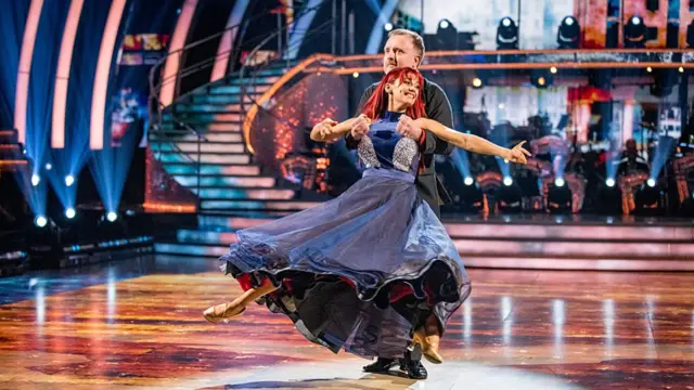 Chris McCausland holding Dianne Buswell as she jumps in the air on the Strictly dancefloor