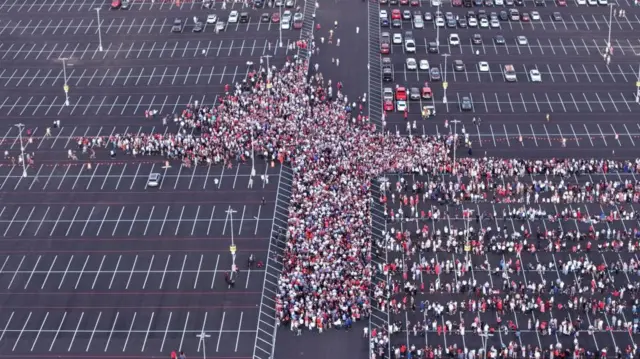 A birds-eye view of crowds of people arriving at the carpark