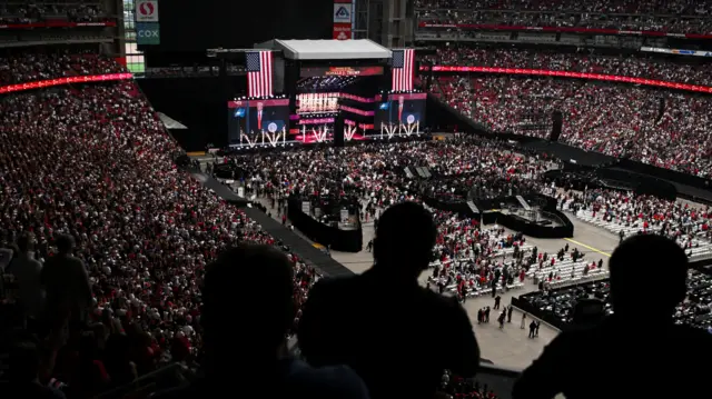 The State Farm Stadium is photographed from high in the stands showing them to be mostly full with some people standing in the pit.