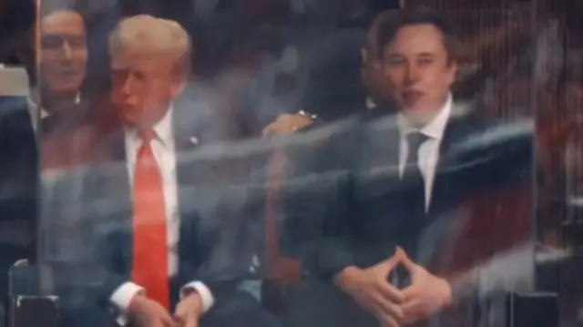 Musk sitting next to Trump