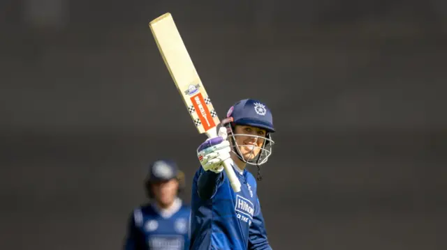 Georgia Adams raises her bat to acknowledge her half-century