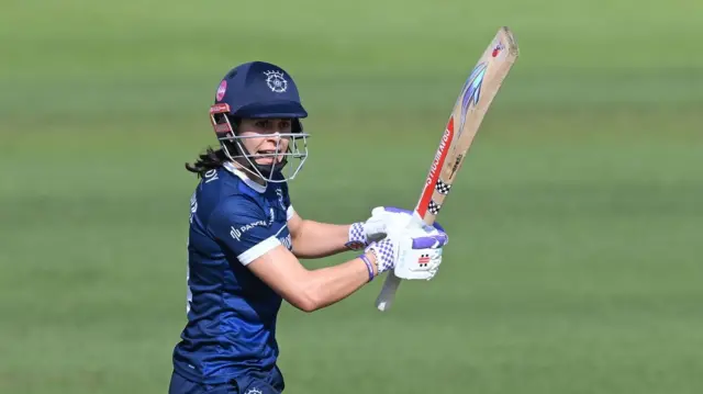 Maia Bouchier, with bat raised, watches as she hits a shot through the offside