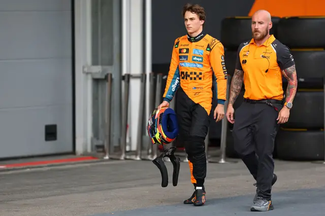 Oscar Piastri walks back to the paddock with a member of the McLaren team