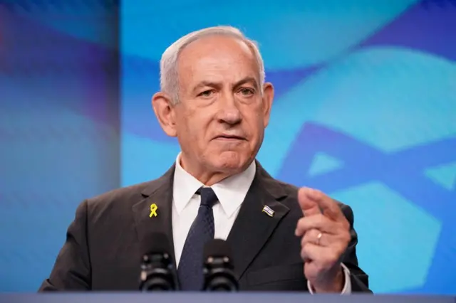 Netanyahu, who has combed over grey hair and wears a suit, points as he leads a press conference