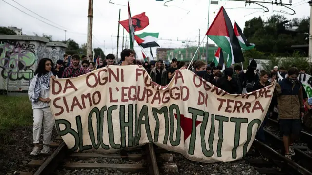 Pro-Palestinians protesters hold a banner reading "Let's block everything" as they walk on railway tracks during a nationwide strike organized by the Unione Sindacale di Base (USB Union) in Turin