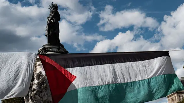 A Palestinian flag hangs in front of a statue in Paris