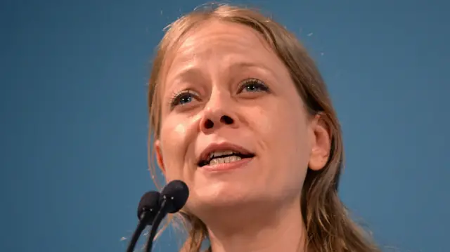 Sian Berry, a middle aged blonde woman, speaks into a microphone at a public event.