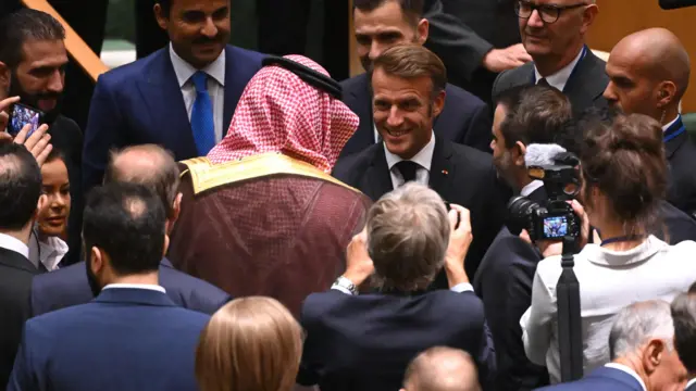 Emmanuel Macron shakes hands with Saudia Arabia's foreign minister as the pair are surrounded by press and UN members