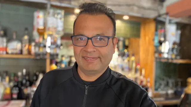 Jyotirmoy Dewan behind the bar in his pub