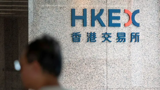 A blurry head of a man in the foreground, with HKEX sign on a wall in front of him