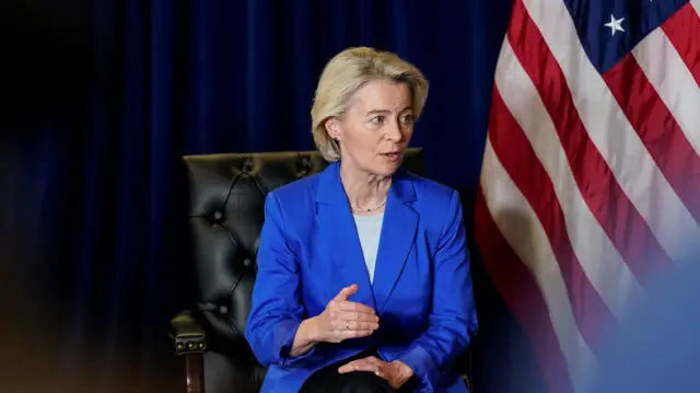 Von der Leyen in a blue suit by an American flag