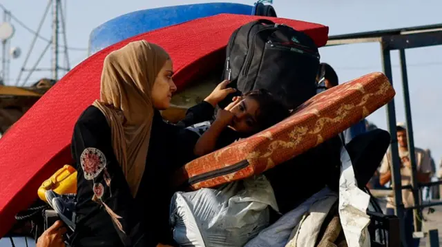 A mother takes care of her child as they leave Gaza City following Israeli stikes