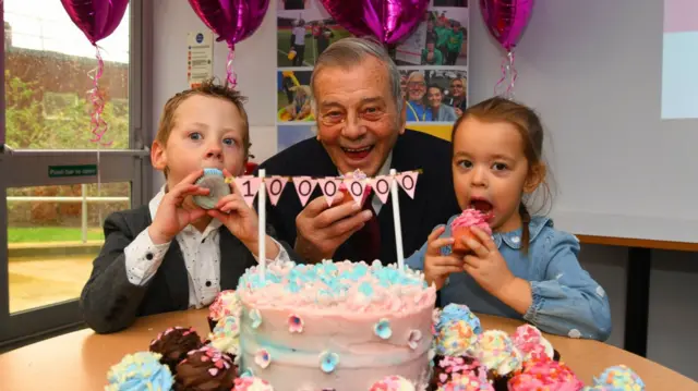 Dickie with two children eating cupcakes at a charity celebration