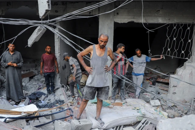 A Palestinian man looks on as he inspects the site of Israeli strikes on houses at Shati refugee camp
