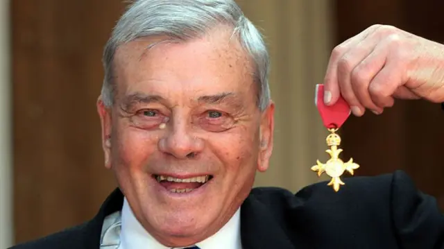 Dickie Bird holds up his Officer of the British Empire (OBE) medal.