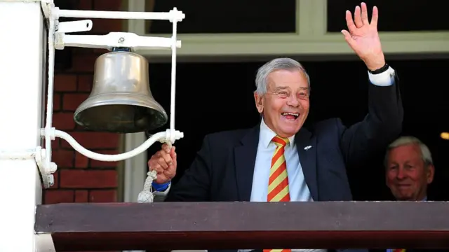 Dickie Bird waving as he rings a bell