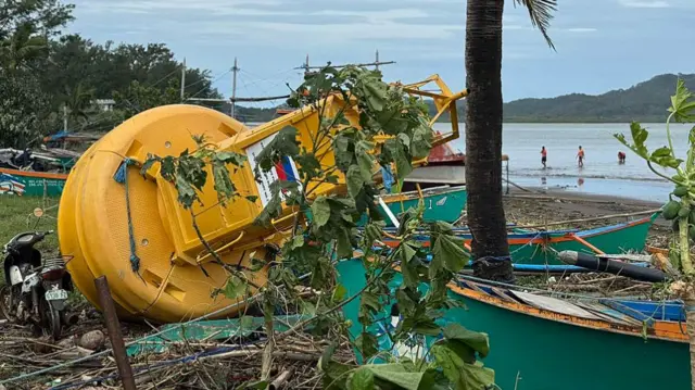 A yellow buoy lying among plants and debris