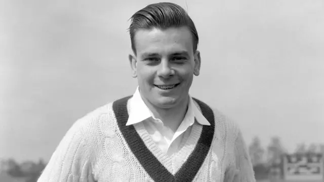 A black and white photo of a man in a cricket jumper and shirt