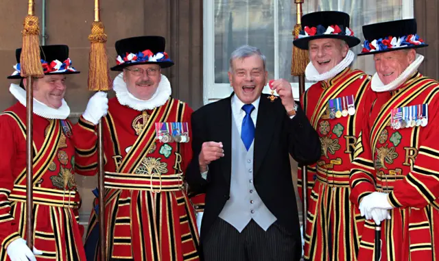 Dickie Bird holding medal with four beefeaters