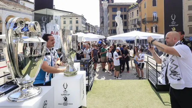 Tottenham fans take pictures next to Uefa trophies before the Super Cup final in Udine
