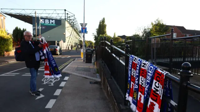 Half and half scarves hang on a railng near the ground
